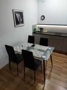 a glass table with four chairs and a kitchen at Apartamenty Lawendowy Zakątek 5 in Opole