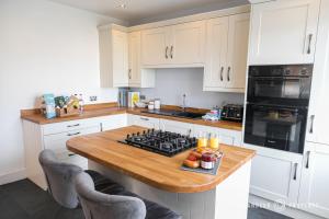 cocina con armarios blancos y encimera de madera en Large 2bed House, Heart of Upper Parkstone, Close to Beach - Buckland Heights, en Poole