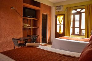 a bedroom with a bed and a table and a television at Hotel Quinta Maya in Flores