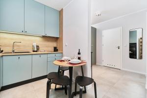a kitchen with a small table and two stools at Promenady Green Apartments by Renters in Wrocław