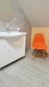 einen orangenen Stuhl im Bad mit Waschbecken in der Unterkunft Willa Brodnica in Brodnica Dolna