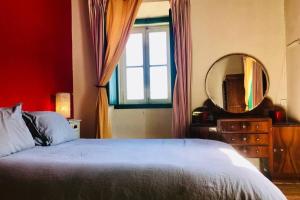 a bedroom with a bed and a mirror and a window at La Casa Flores, maison traditionnelle portugaise in Odeceixe