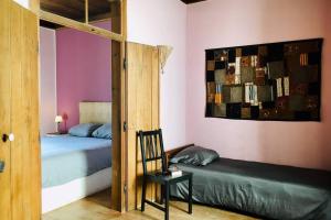a bedroom with two beds and a chair and a mirror at La Casa Flores, maison traditionnelle portugaise in Odeceixe