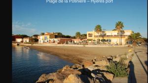 a beach with buildings and palm trees and water at Horizon Plage in Hyères
