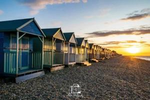a row of beach huts on the beach at sunset at Top floor flat with sea view in Herne Bay