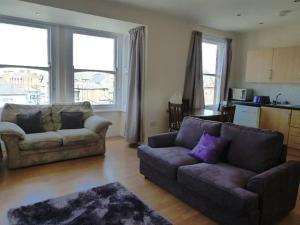 a living room with two couches and a kitchen at Top floor flat with sea view in Herne Bay