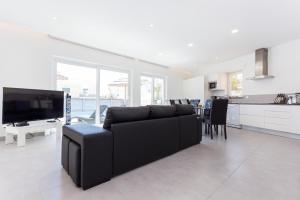sala de estar con sofá negro y cocina en CoolHouses Algarve, Casa Marisa, V5 Burgau, en Burgau