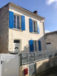 a white house with blue shutters and a fence at Maison de vacance au coeur du village in Saint-Trojan-les-Bains