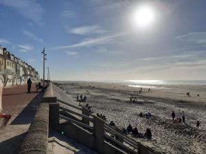 a group of people sitting on the beach at Les Obiones, vue latérale mer, Fort Mahon Plage, magnifique studio cabine 4p, avec balcon , parking privé gratuit, wifi, classé 2 étoiles, exposition plein sud en Baie de Somme in Fort-Mahon-Plage
