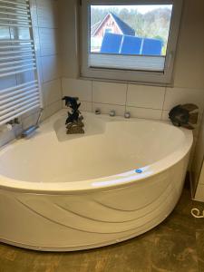 eine große weiße Badewanne im Bad mit Fenster in der Unterkunft Maisonette zum Weststrand in Prerow