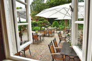 a patio with tables and chairs and an umbrella at Klosterschänke Hude Hotel Ferienwohnungen Restaurant Café in Hude