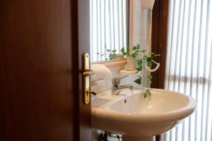ein Badezimmer mit einem Waschbecken und ein Fenster mit einer Pflanze in der Unterkunft Il Melo Residence in Porto Torres