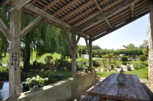 una mesa de picnic de madera bajo una pérgola de madera en La Ferme Blanche, en Cussay