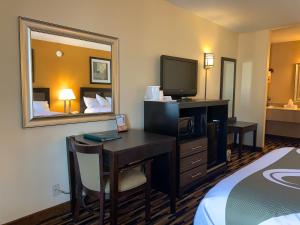 a hotel room with a desk with a television and a bed at Quality Inn University Area in Troy