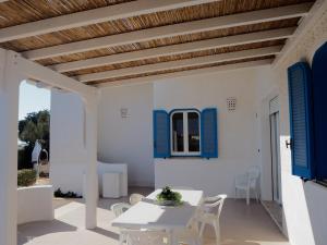 un patio con persianas azules, mesa y sillas en Villa Oltremare, en Torre Suda