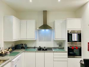 a white kitchen with white cabinets and a sink at Higher Lane House in Plymouth