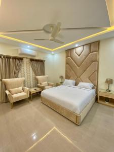 a bedroom with a large bed and two chairs at Continental boutique House in Islamabad