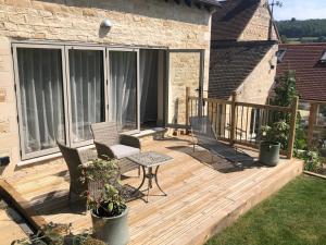 a wooden deck with chairs and a table at Cotswold Lodge in Painswick