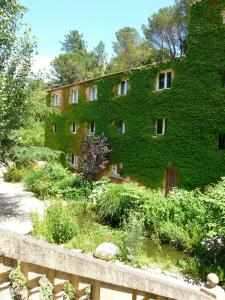 a building covered in green ivy next to a garden at Apart'Hôtel Les 4 Sources in Anduze