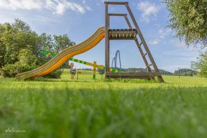 a playground with a slide in a grassy field at Gasthof Neuhofen in Eugendorf