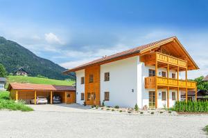 a large white building with a wooden roof at Chiemgauferienwohnungen - Maier in Unterwössen