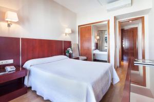 Un dormitorio con una gran cama blanca y un baño. en Crisol Riosol, en León