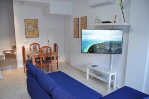 sala de estar con sofá azul y TV de pantalla plana en Villachipi, en Chipiona
