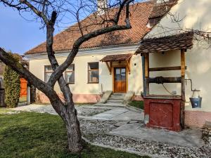 a white house with a red door and a tree at Gästehaus Honigberg next to the Fortified Church of Harman in Hărman
