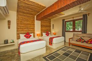 a bedroom with two beds and a chair and a couch at Tierra Maya Hotel Spa & Sanctuary in Bacalar +92 photos