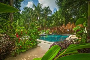 a swimming pool in the middle of a garden at Tierra Maya Hotel Spa & Sanctuary in Bacalar