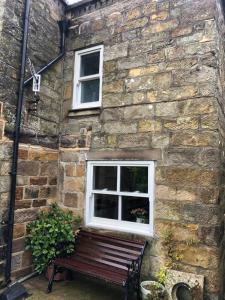 a bench in front of a stone building with two windows at Carlton Cottage, Castleton in Castleton