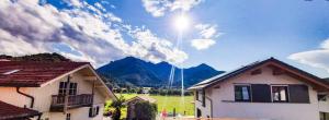Blick auf einen Berg mit Häusern und die Sonne in der Unterkunft Ferienwohnung Reisenauer in Marquartstein