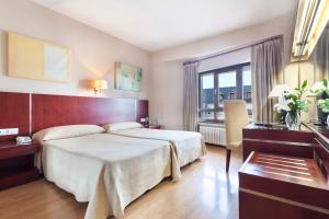 Una habitación de hotel con una cama grande y una ventana. en Crisol Riosol, en León
