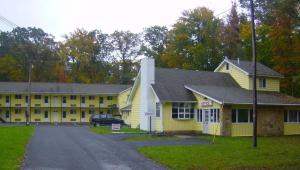 um edifício amarelo com um carro estacionado em frente em Country Place Inn and Suites White Haven em White Haven