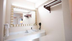 a bathroom with a sink and a mirror at Magnuson Extended Stay and Suites Airport Hotel in Irving +19 photos