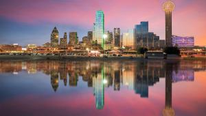 a city skyline at night with a reflection in the water at Magnuson Extended Stay and Suites Airport Hotel in Irving