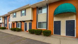 uma fila de edifícios de apartamentos com portas azuis e arbustos em Magnuson Hotel Extended Stay Canton Ohio em Lake Cable