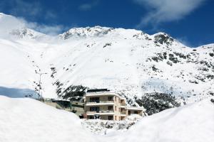 a building in front of a snow covered mountain at Apartmenthaus Enzian Hochsölden in Sölden