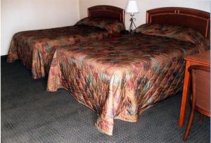 a hotel room with two beds and a table at Will Rogers Inn in Claremore
