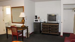 Habitación de hotel con TV y escritorio con sidx de mesa en Golden Wheat Budget Host Inn Junction City, en Junction City