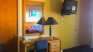 1 dormitorio con escritorio con lámpara y TV en Juniper Motel Madras, en Madras