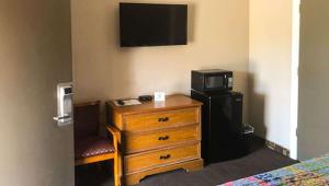 a hotel room with a television and a dresser with a bed at Budget Inn Ardmore OK in Ardmore