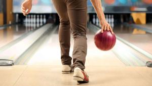 Een persoon gooit een bowlingbal over een bowlingbaan. bij M Star Hotel Covington in Covington