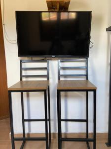 Une télévision à écran plat est installée au-dessus de deux tables de nidification. dans l'établissement Recanto da Paz Ibitipoca com Hidromassagem, à Conceição da Ibitipoca