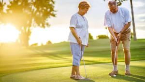 an older couple playing golf on a golf course at Alma Motel in Alma