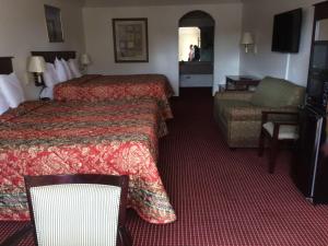 a hotel room with two beds and a chair at Executive Inn Schulenburg in Schulenburg