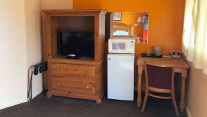 a kitchen with a refrigerator and a table with a tv at Motel Forrest Rockville in Rockville