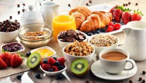 una mesa de desayuno con productos para el desayuno, café y fruta en Magnuson Hotel Fowlerville, en Fowlerville