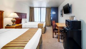 Habitación de hotel con 2 camas y escritorio con TV. en Magnuson Grand Hotel and Conference Center Tyler, en Tyler