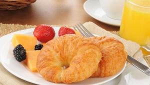 einen Teller mit einem Croissant und Obst auf dem Tisch in der Unterkunft Magnuson Hotel Country Inn in Ishpeming